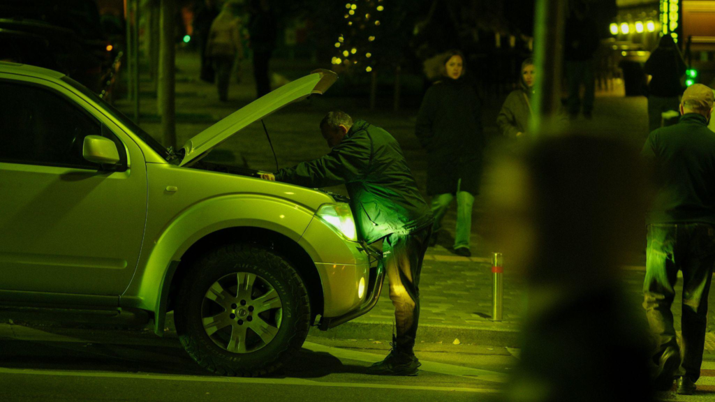This photo shows a man looking at a car engine. 