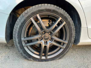 Car with a flat tire requiring a damage-free tire change.