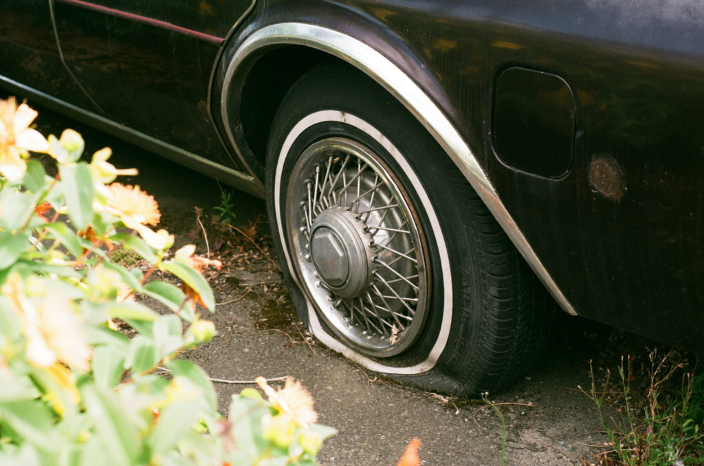 A car with a severely damaged tire stranded on the roadside.
